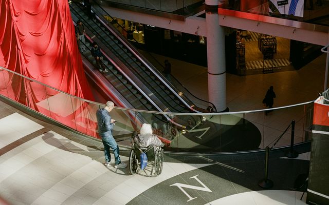 Menschen in einem öffentlichen Gebäude, darunter eine Person im Rollstuhl